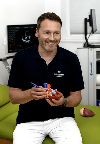 Kardiologe Christian Krafzick mit einem Modell des Herzens